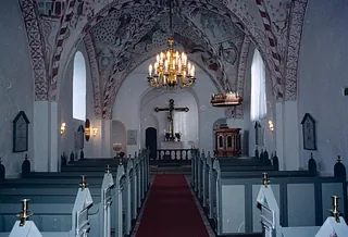 Kircheninnenraum mit Altar und Bänken.