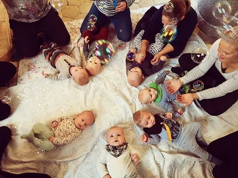 Babys und Erwachsene spielen mit Seifenblasen.