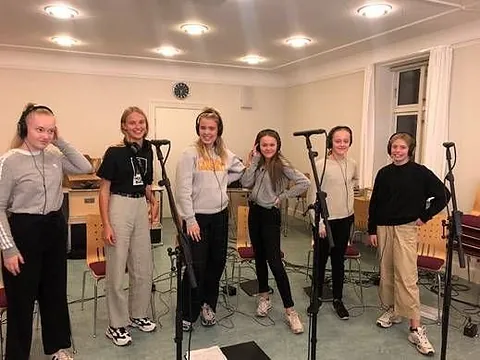 Sechs junge Frauen mit Kopfhörern und Mikrofonen.