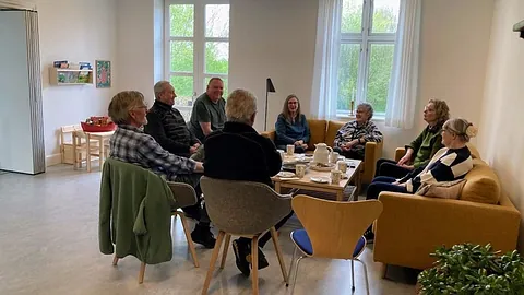 Gruppe von Senioren unterhält sich in einem Gemeinschaftsraum.